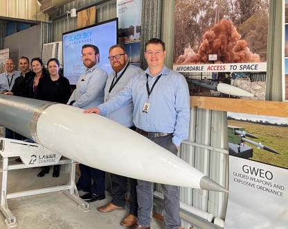 A photo of seven people standing alongside a rocket.