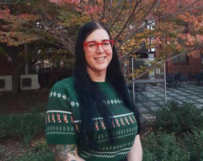 Photo of Deanne Fisher standing in front of an autumn tree on a university campus