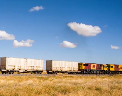 Train carrying shipping containers in country area 