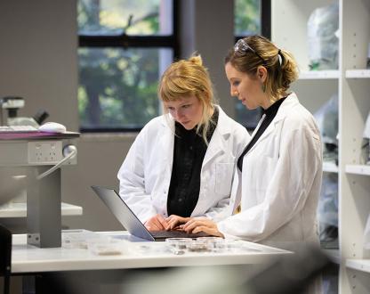 Photo of 2 scientist looking at a laptop in a laboratory