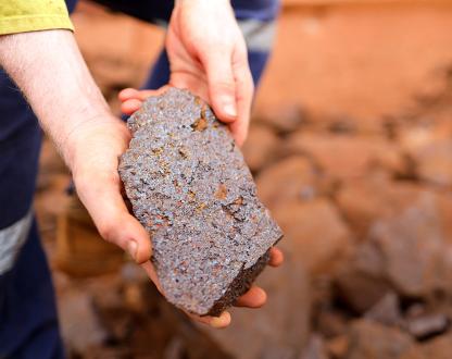 Closeup photo of a pair of hands holding iron ore.