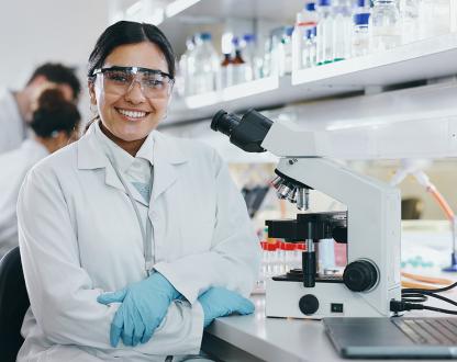 Female scientist dressed in a lab coat. In a modern laboratory with microscope.