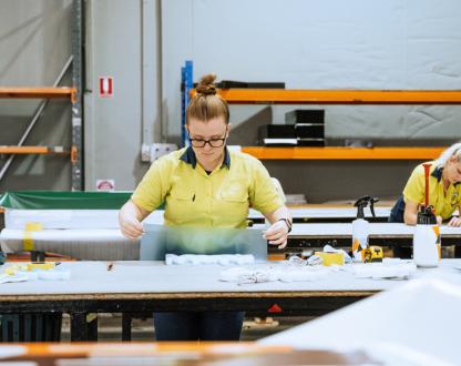 Photo of a woman working with moulded plastic and signage in an industrial warehouse