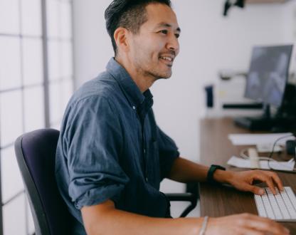 Close up photo of an office worker sitting at their desk and working at a computer