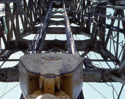 Photo of offshore petroleum infrastructure, looking upward through scaffolding toward the sky.