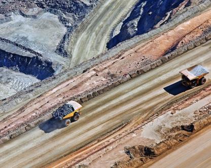 Two mining trucks drive along a road.