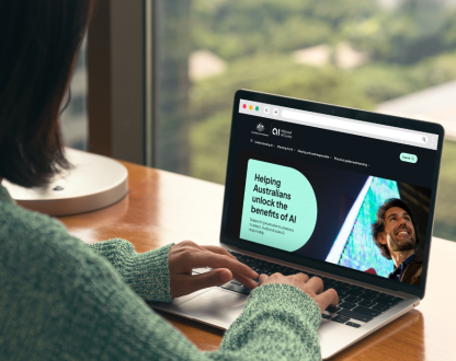Person typing on a laptop with the screen showing the home page of the Ai.gov.au website