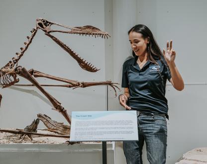 Woman palaeontologist explaining a dinosaur skeleton in an exhibition