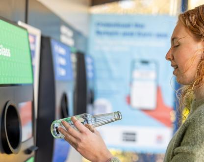 Young woman using a bottle recycling machine. 