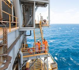 2 workers in fluro orange  on an oil rig in the ocean